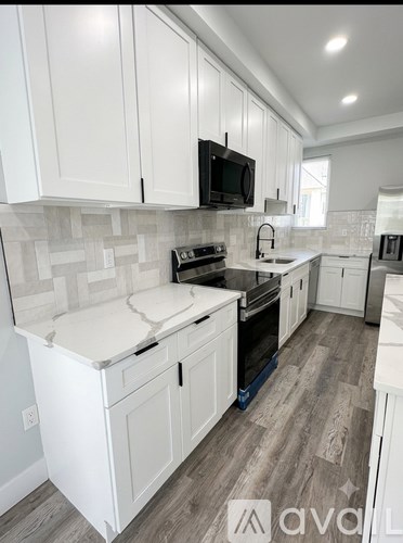 A kitchen with white cabinets and a black microwave.