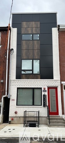 A black and white building with a red door.