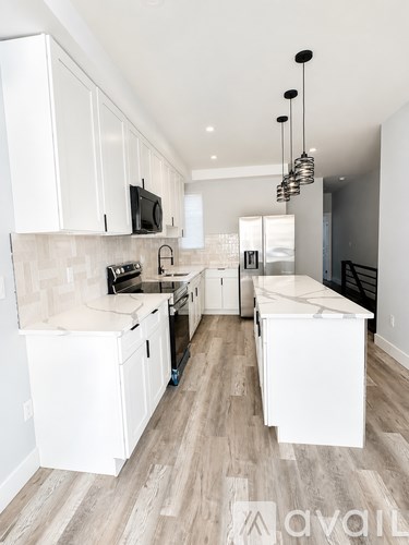 A kitchen with white cabinets and a wooden floor.