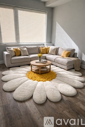 A living room with a grey couch, a yellow rug, and a wooden coffee table.