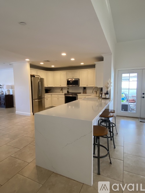 A kitchen with a white island and bar stools.