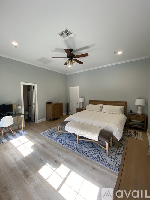 A bedroom with a bed, a chair, and a ceiling fan.