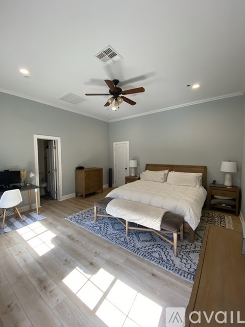 A bedroom with a bed, a chair, and a ceiling fan.