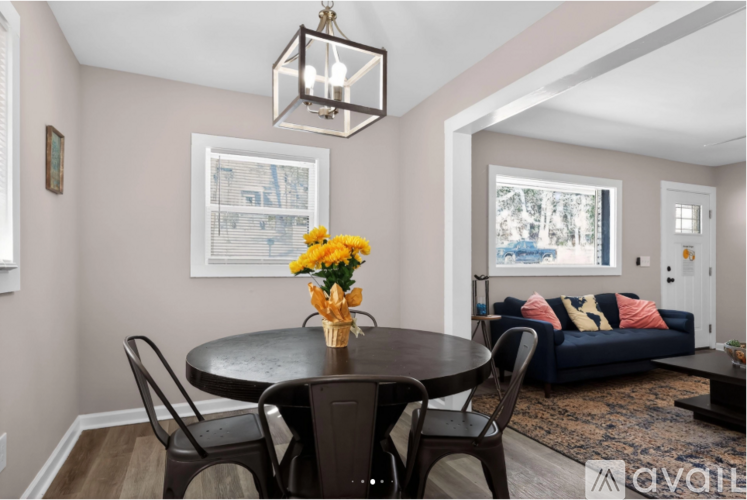 A dining room with a table set for two and a couch in the background.