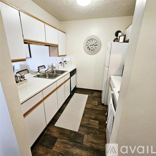 A small kitchen with white cabinets and a white fridge.