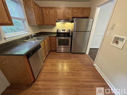 A kitchen with wooden cabinets and a stainless steel refrigerator.