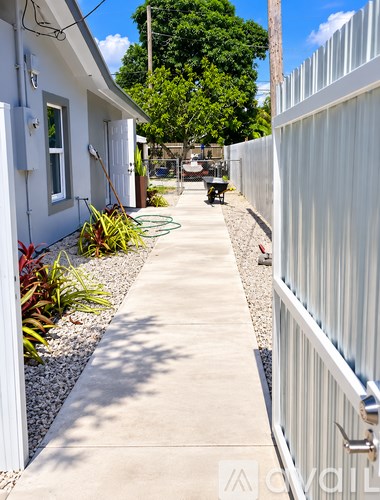 A white fence runs along the side of a concrete path.