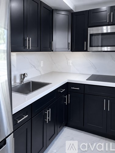 A kitchen with black cabinets and a white floor.