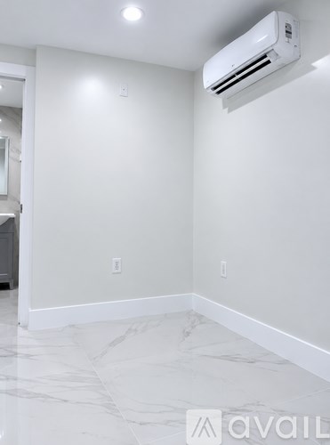 A white hallway with a marble floor leads to a kitchen.