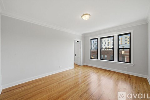A room with wooden flooring and a window with a view of a building.