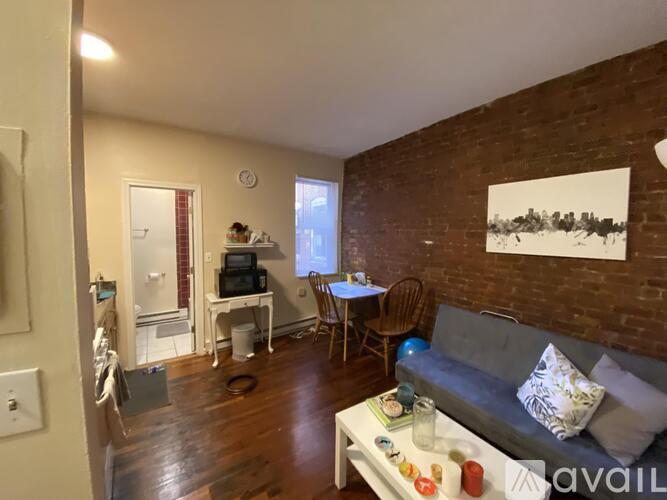 A living room with a grey couch and a brick wall.