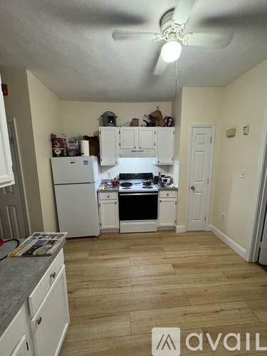 A kitchen with white cabinets and a wooden floor.