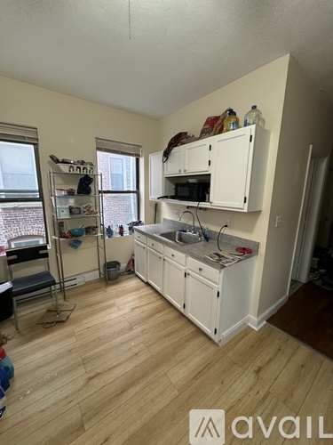 A kitchen with white cabinets and wooden floors.