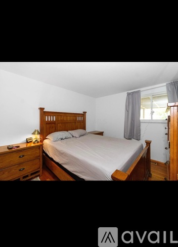 A bedroom with a bed, nightstand, and window.