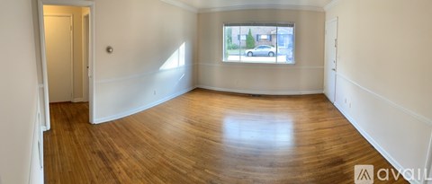 A room with wooden floors and a window showing a street view.