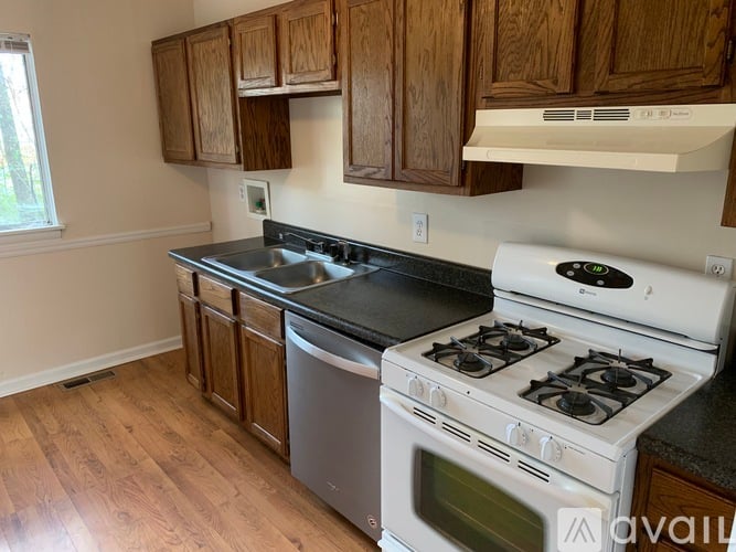 A kitchen with a white stove and wooden cabinets.
