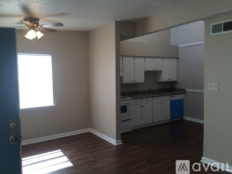 A kitchen with white cabinets and a blue trash can.