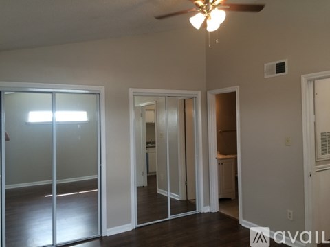 A room with a ceiling fan and sliding glass doors.
