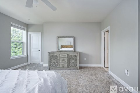A bedroom with a white bedspread and a grey cabinet with a mirror on top.