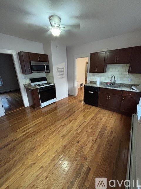 A kitchen with wooden floors and dark brown cabinets.