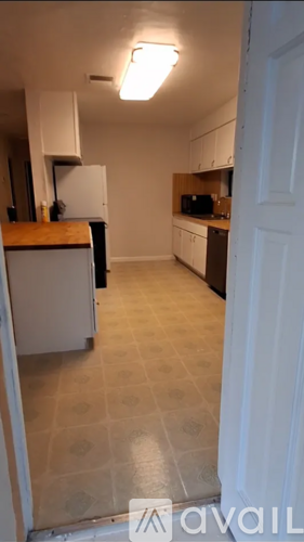 A kitchen with white cabinets and a wooden counter top.