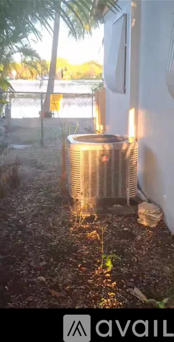 A silver air conditioner unit is placed on a concrete floor outside a building.