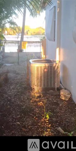A silver air conditioner unit is placed on a concrete floor outside a building.