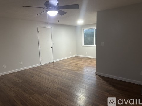 A room with a ceiling fan and wooden flooring.