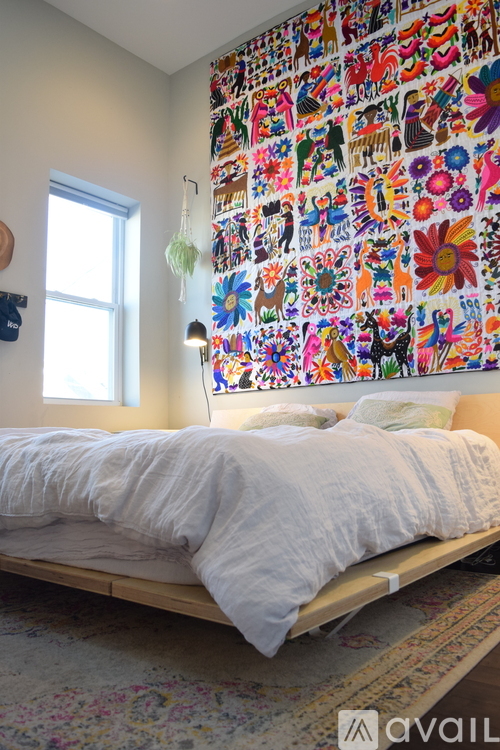 A bedroom with a bed and a wall covered in pictures.
