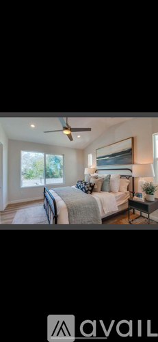 A bedroom with a bed, a ceiling fan, and a window.