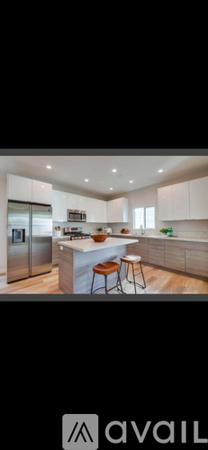 A modern kitchen with a refrigerator, stove, and bar stools.