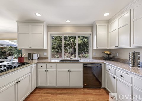 A kitchen with white cabinets and a wooden floor.