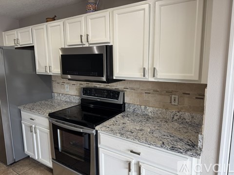 A kitchen with white cabinets and black appliances.