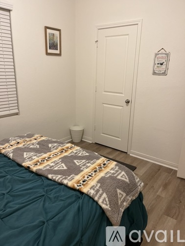 A bedroom with a bed covered in a patterned blanket and a white door.
