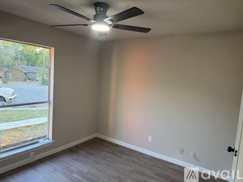 A room with a window that has a view of a yard and a building.