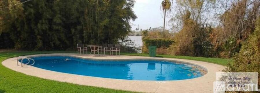 A small, kidney-shaped pool with a white fence around it.
