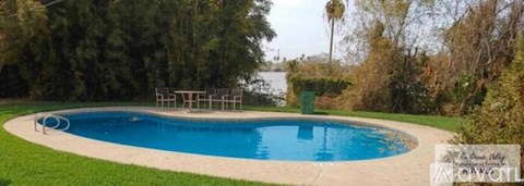 A small, kidney-shaped pool with a white fence around it.