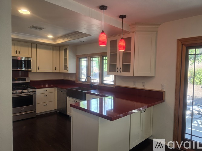 A kitchen with white cabinets and a red countertop.