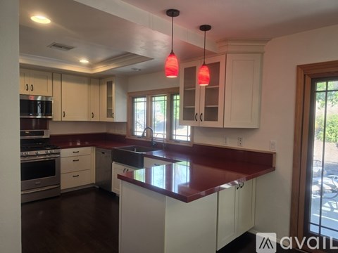 A kitchen with white cabinets and a red countertop.