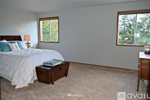 A bedroom with a bed, nightstand, and window.