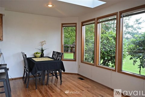 A dining room with a table set for two and a view of the backyard.
