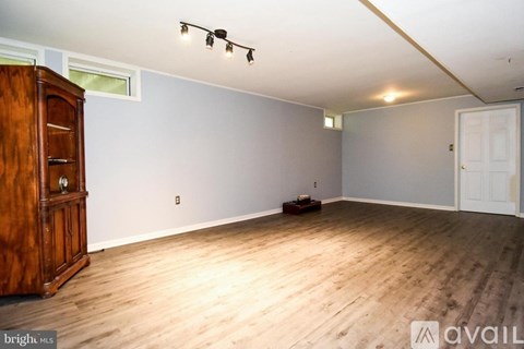 A room with wooden flooring and a wooden cabinet with a window above it.