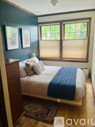 A bedroom with a bed and a window with blinds.