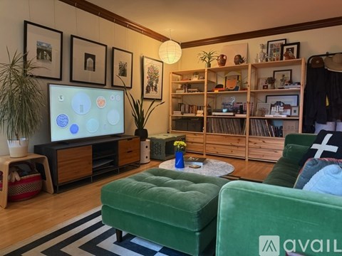 A living room with a green couch and a television displaying a colorful screen.