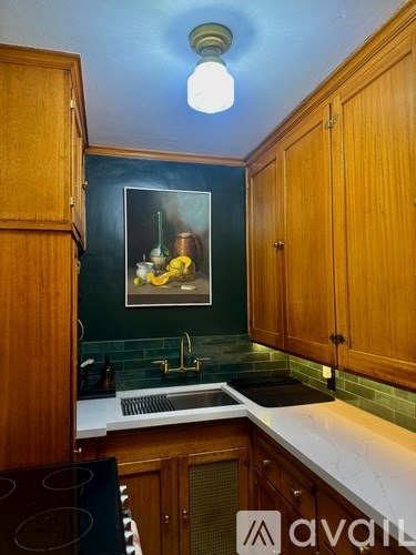 A kitchen with wooden cabinets and a painting of a still life on the wall.