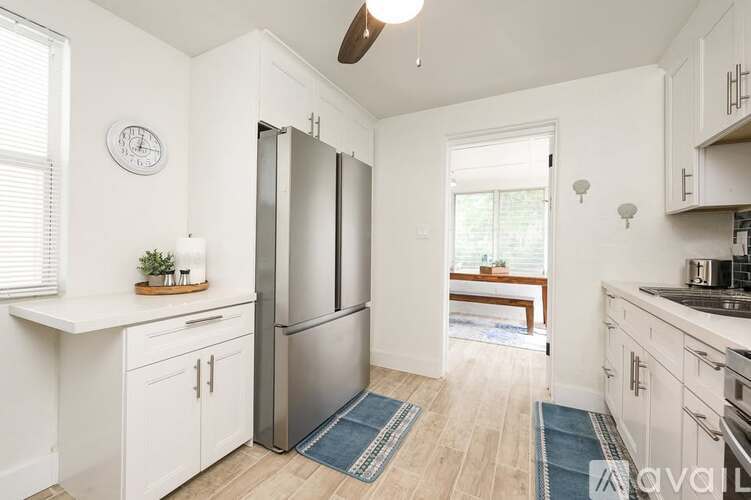 A kitchen with white cabinets and a stainless steel refrigerator.
