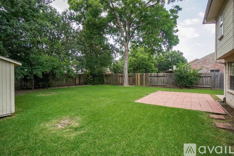 A backyard with a green lawn and a red brick patio.