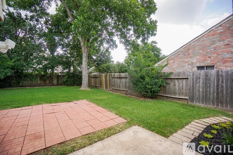 A backyard with a brick patio and a wooden fence.