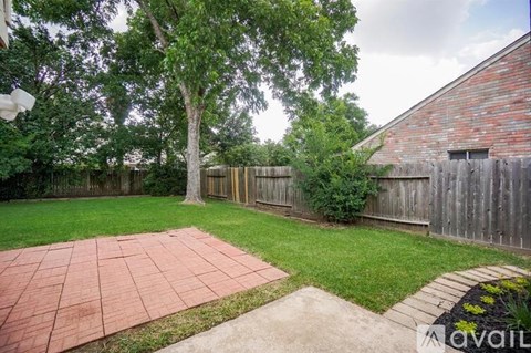 A backyard with a brick patio and a wooden fence.