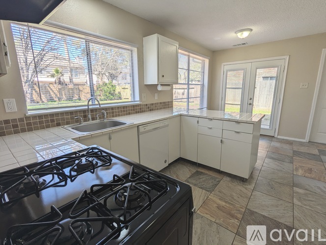 A kitchen with a black stove top and white cabinets.